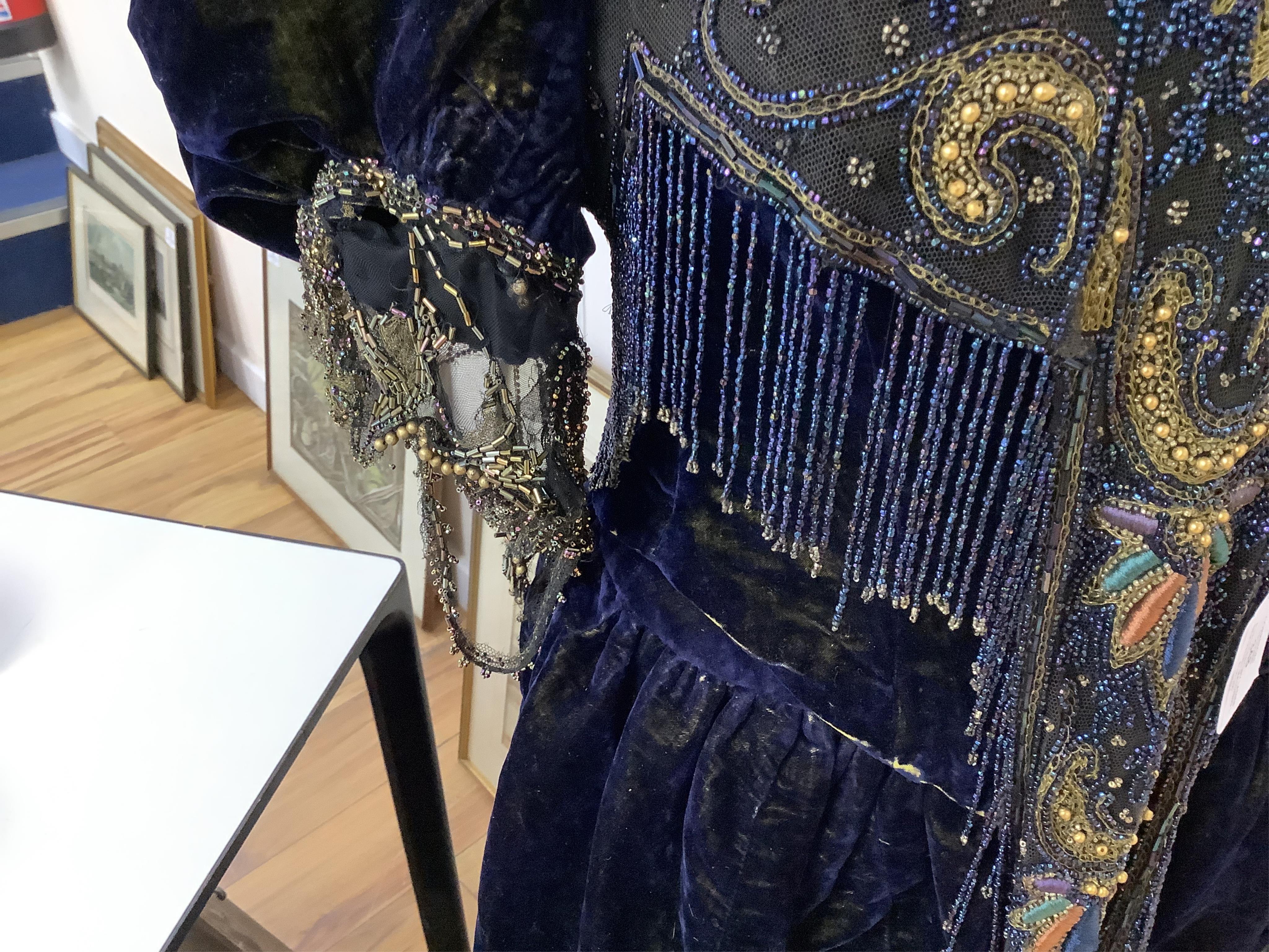 A 19th century ladies silk velvet matching long sleeved jacket/bodice, and skirt, together with another matching short sleeved bead worked bodice and white feather headdress.(4). Cape 106cm long. Condition - Both bodices